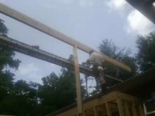 Carpenter setting a ridge beam over a new addition frame — Ice Dam Removal by Roofing Brothers in Longwood