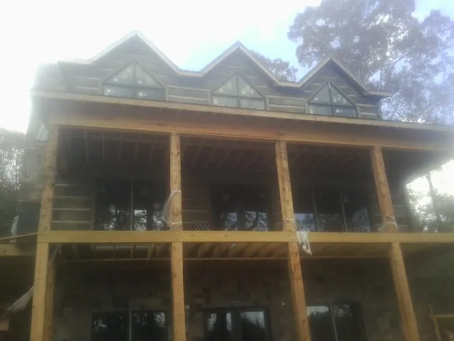 Dormers and porch framing on a large log home under construction — Roof Coating work by our crew in Longwood