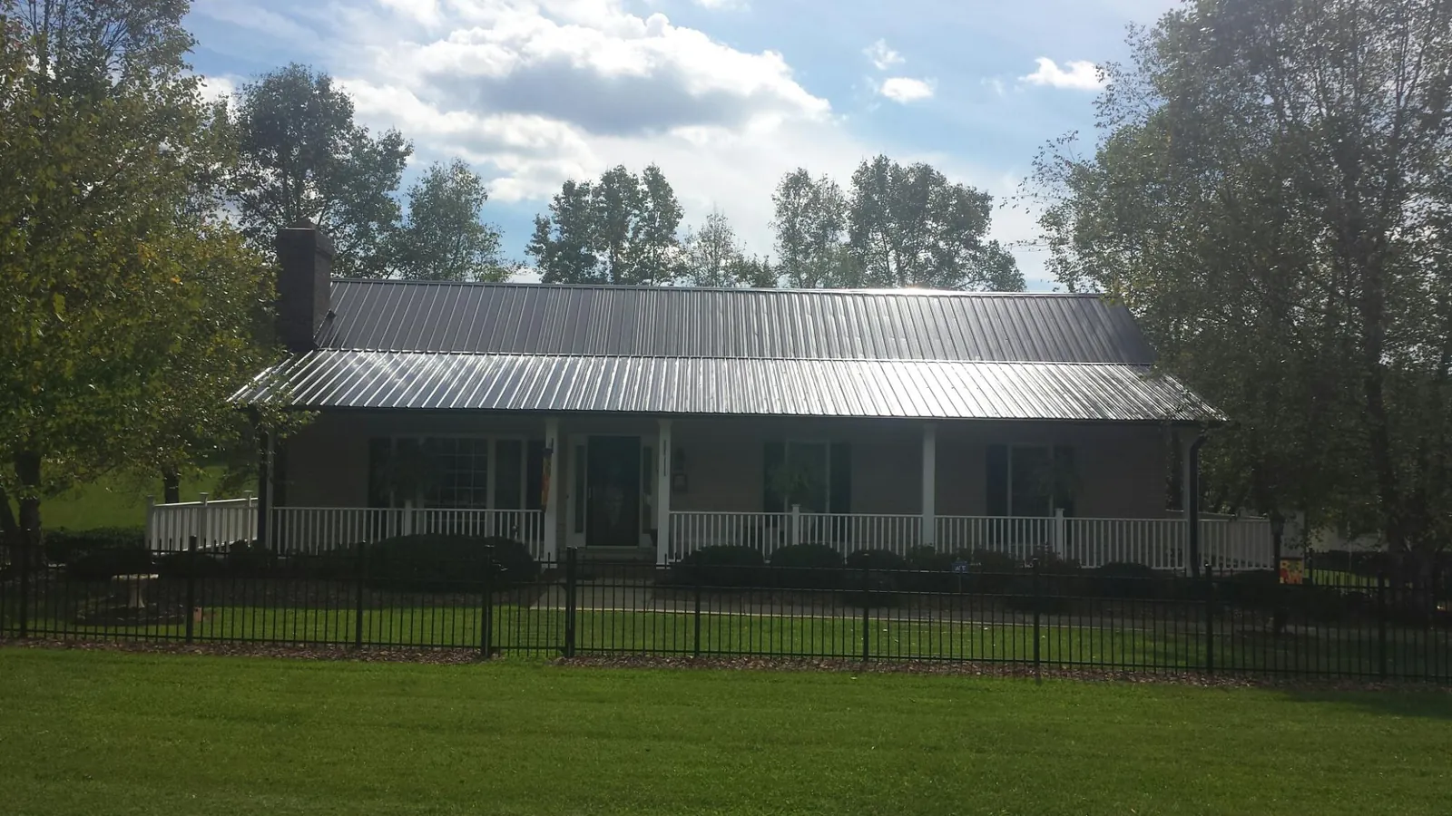 Gray metal roof on a brick ranch with a full width front porch — Gutter Guard Installation work by our crew in Longwood