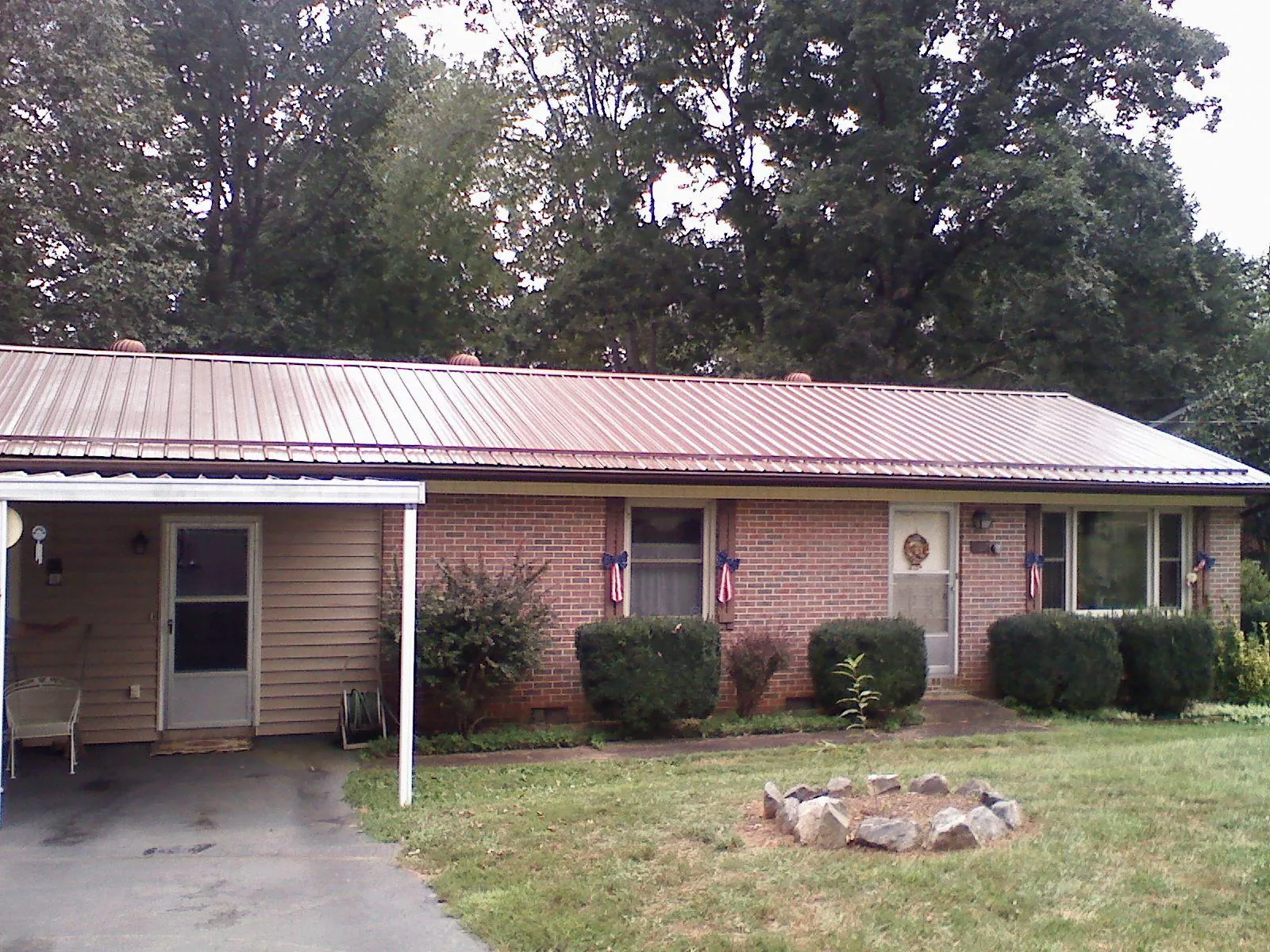 Bronze metal roof and carport on a brick ranch home — Roof Repair work by our crew in Longwood